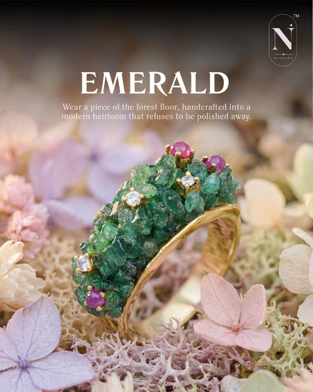 Gold ring with natural  emeralds and pink  ruby beads on a natural background with flowers.