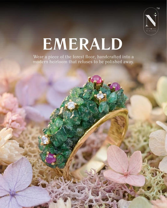 Gold ring with natural  emeralds and pink  ruby beads on a natural background with flowers.