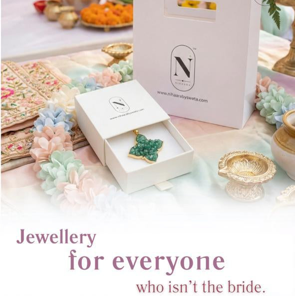Jewellery box with green emerald gemstone on a table with decorative items, featuring text 'Jewellery for everyone who isn't the bride.'.